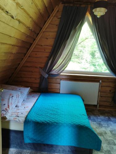 a bed in a wooden room with a window at Domek Magellan Cisna 11 in Cisna