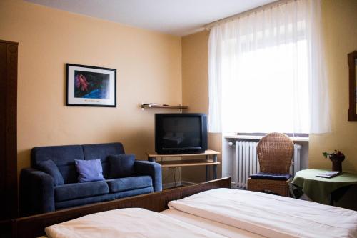a bedroom with a bed and a couch and a tv at Hotel Westrich in Baumholder