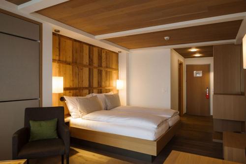 a bedroom with a bed and a chair in it at Adler Adelboden in Adelboden