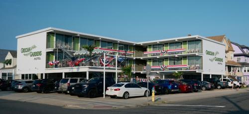 a large building with cars parked in a parking lot at Grecian Garden Motel in North Wildwood