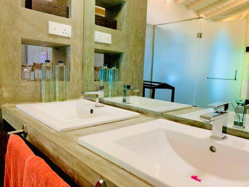 a bathroom with two sinks and a large mirror at Suite Lanka in Hikkaduwa