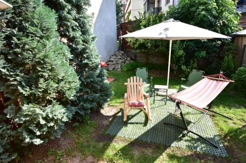 two chairs and an umbrella and a hammock in a yard at Homey Luxury- entire house, free parking, yard in Cluj-Napoca