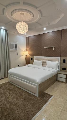 a bedroom with a large bed and a chandelier at نسمة كيان للشقق المخدومة Nasma Kayan Serviced Apartments in Jeddah
