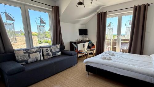 a bedroom with a bed and a couch and windows at Angelika in Swarzewo