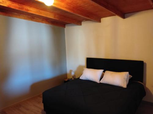 a bedroom with a black bed with two white pillows at Casa Atitur in San Pedro de Atacama