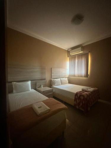 a hotel room with two beds and a window at Hotel Matrin in Barretos
