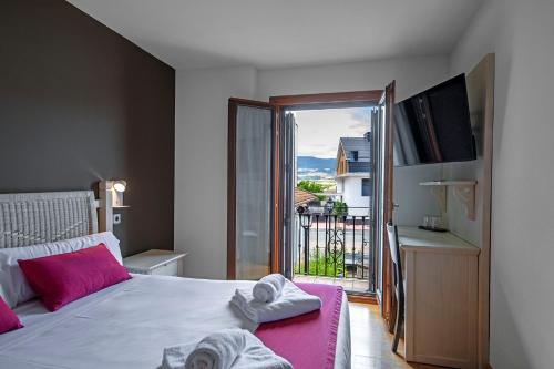 a bedroom with a bed with pink pillows and a balcony at Hotel Casa Azcona in Zizur Mayor