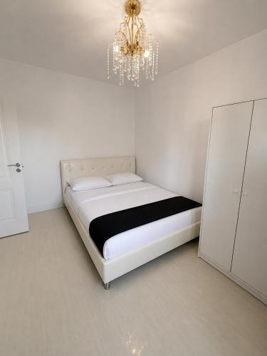 a white bedroom with a bed and a chandelier at YDA Apartament's in Baciu