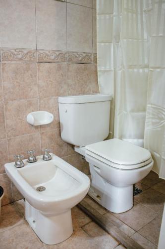 a bathroom with a white toilet and a sink at Hotel Del Parque in Corrientes