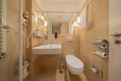 a small bathroom with a toilet and a sink at Juno Hotel Bremen City in Bremen
