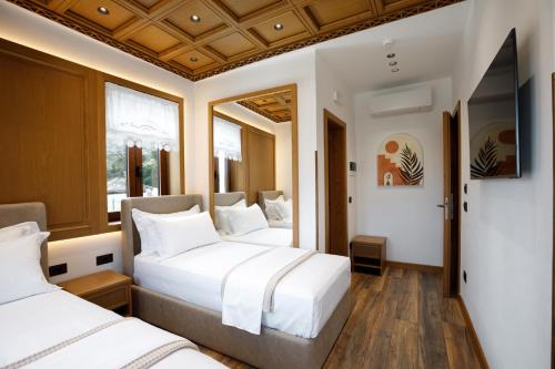 a bedroom with two beds and a mirror at Vila Mantho in Gjirokastër