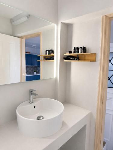a white bathroom with a sink and a mirror at The Sunset by KHI in Kithnos