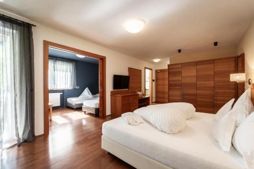 ein Schlafzimmer mit einem großen weißen Bett und einem Fernseher in der Unterkunft Bad Ratzes in Seis am Schlern