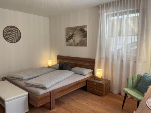 a bedroom with a bed and a chair and a window at Haus Priller in Sillian