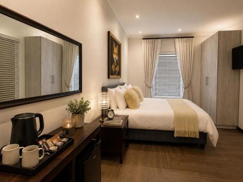 a bedroom with a bed and a desk and a mirror at ACRE on Albatros in Gqeberha