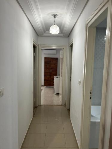 a hallway with white walls and a ceiling with a door at Appartement 2 chambres à 250m de la plage, propre & bien équipé in Monastir