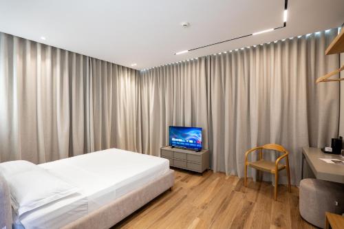 a bedroom with a bed and a desk and a television at EFFÉI Boutique Hotel in Sarandë