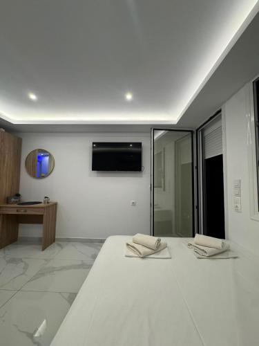 a bedroom with a white bed and a television on the wall at Premium Studio Family in Paralia Katerinis