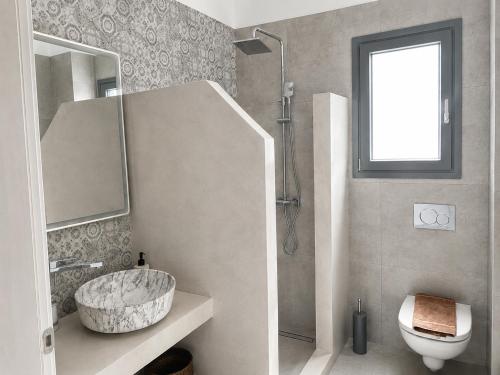ein Badezimmer mit Waschbecken, Toilette und Spiegel in der Unterkunft Aqualis in Adamas