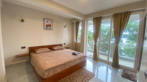 a bedroom with a bed and large windows at Stayat77 in Karsiyang