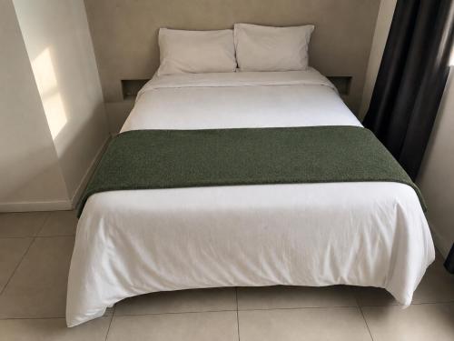a white bed with a green blanket on it at Studiohaus Alvorada in São Paulo