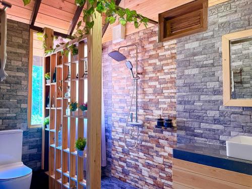 a bathroom with a toilet and a brick wall at Cinnamon River Cabana in Ella