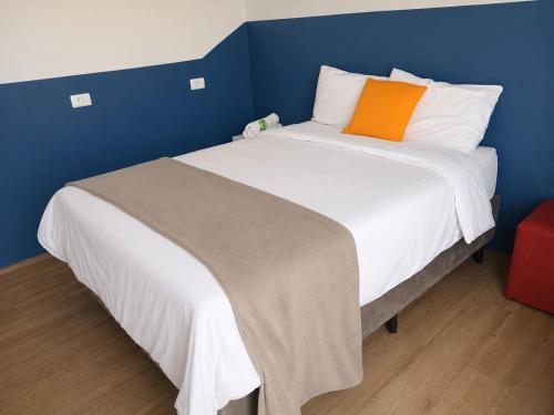 a bed with an orange pillow on top of it at Studiohaus Pertence in São Paulo