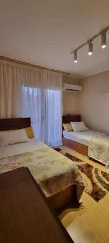 a bedroom with two beds and a window at Tara Home 204 in Sheikh Zayed