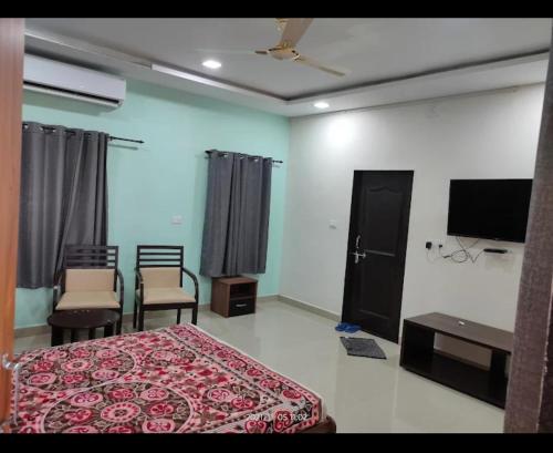 a bedroom with a bed and chairs and a flat screen tv at Rail connect hotel statue of unity in Kevadia