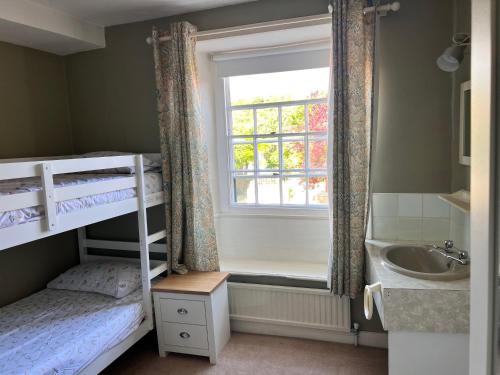a bedroom with bunk beds with a window and a sink at Towler's Chemist in Kirkbymoorside
