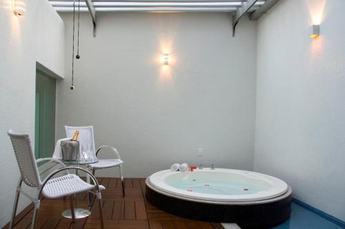 uma banheira num quarto com uma mesa e cadeiras em Motel Chalet (Adults Only) em Belo Horizonte