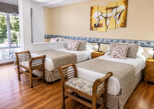 Zwei Betten in einem Zimmer mit zwei Stühlen und einem Tisch in der Unterkunft Hotel Sol del Sur in Esquel