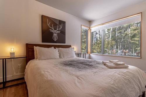 a bedroom with a large bed with a large window at Welcome to La Cabine de Charlevoix in Petite-Rivière-Saint-François