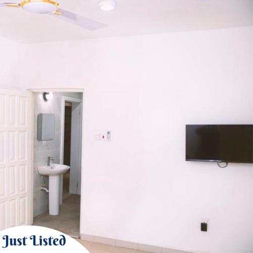 ein Badezimmer mit einem Fernseher an einer weißen Wand in der Unterkunft Omane Homes in Cape Coast