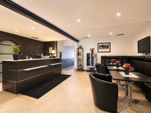 a restaurant with black chairs and tables and a bar at Hotel Kaiserhof in Lehrte