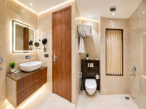 a bathroom with a sink and a toilet and a mirror at Hotel The Luxury Delhi Airport in New Delhi