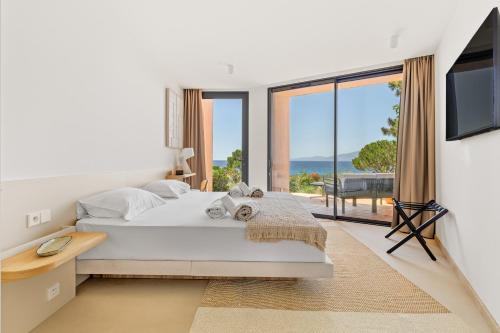 a white bedroom with a large bed and a large window at La maison de simon in Pietrosella