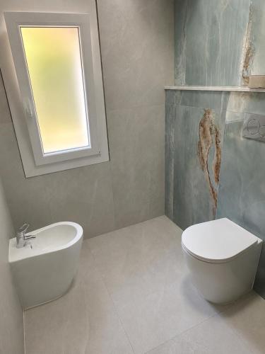 a bathroom with a sink and a toilet and a window at Sa Domo Bonaria - Intero appartamento in Osilo