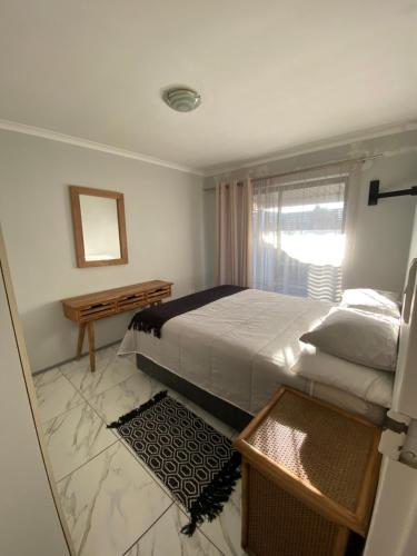 a bedroom with a bed and a table and a window at Spanish Villa- Pet Friendly in Cape Town