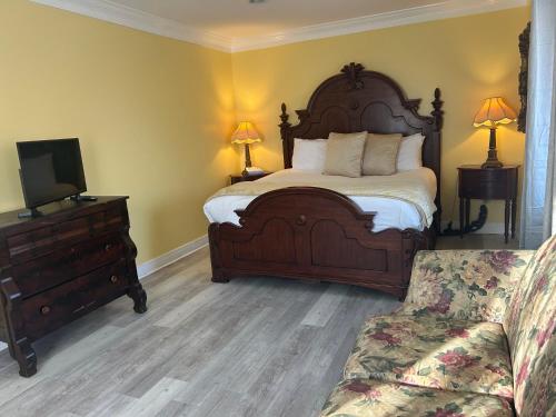 a bedroom with a bed and a couch and a tv at The Inn at Cedar Grove in Vicksburg