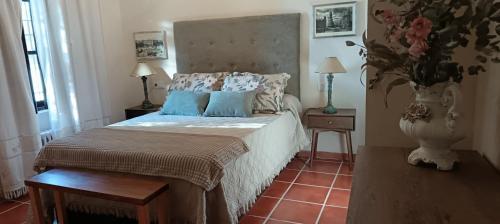 a bedroom with a large bed with blue pillows at Casería El Albercón in Mancha Real
