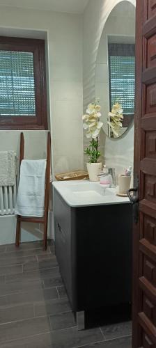 a bathroom with a sink and a mirror and a chair at Casería El Albercón in Mancha Real