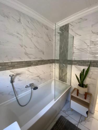 a bathroom with a tub and a glass shower at Spanish Villa- Pet Friendly in Cape Town