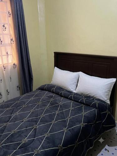 a bed with a blue comforter and white pillows at Petalluxe k24 in Narok