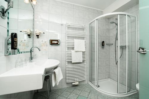 a white bathroom with a sink and a shower at Seehotel Steiner in Seeboden