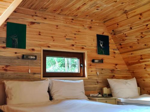 a bedroom with a bed in a wooden wall at Utopija Cabin by Vilovi Botić in Nova Varoš
