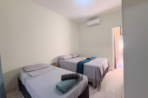 two beds in a room with white walls at Completa e próxima ao Acqualinda in Andradina