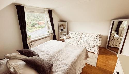 a bedroom with a bed and a couch and a window at Villa lugn och ro in Gustavsberg