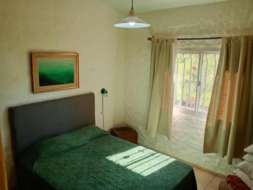 a bedroom with a green bed and a window at Chalet ARMONIA in La Falda