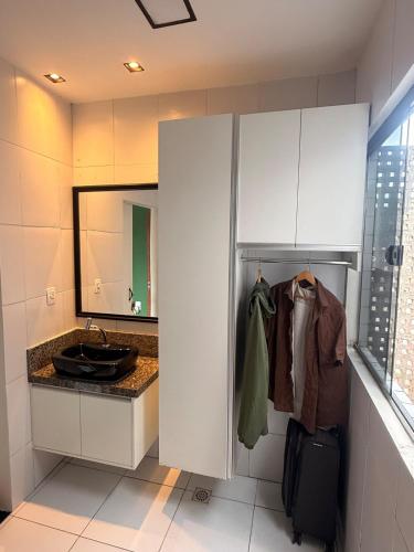 a bathroom with white cabinets and a sink and a mirror at Loft Vava in Campina Grande